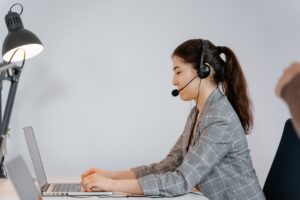 woman wearing headphones is working and talking to someone online using her laptop